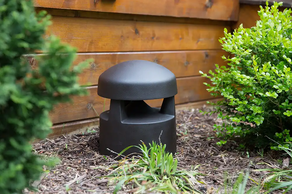 A black garden light speaker sits in the middle of a yard at a Chicago North Shore home.