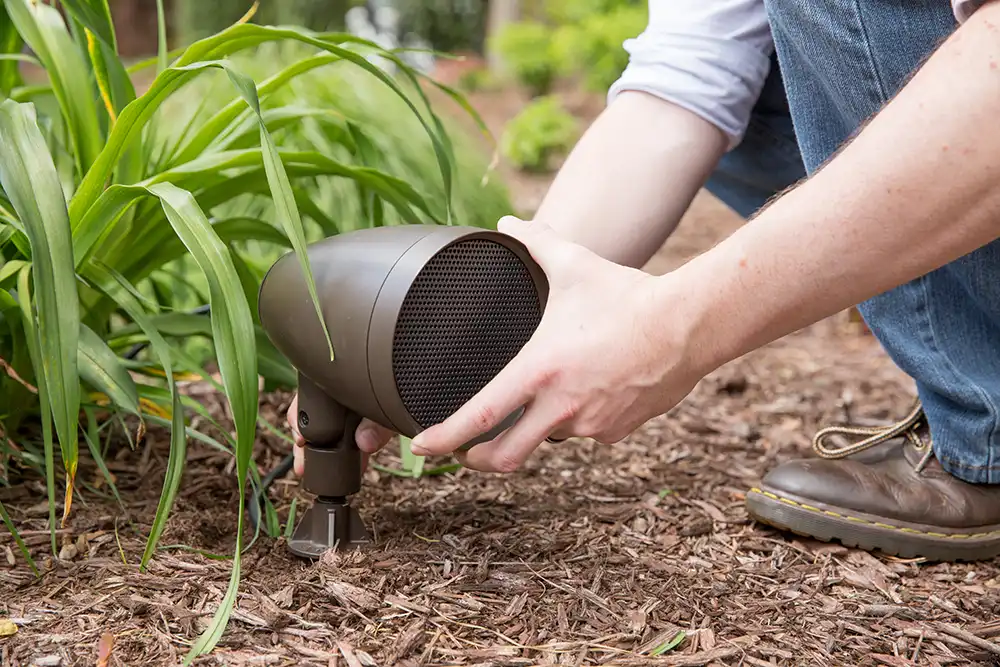 A person putting a speaker in the ground at a Chicago North Shore home.