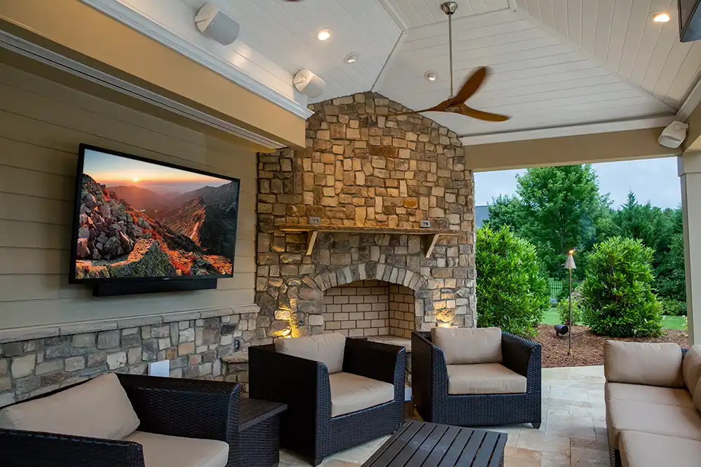 An outdoor living area with a fireplace, TV, and speakers of a Chicago North Shore home.