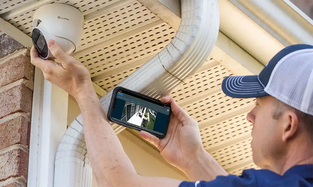 A man using a cell phone to observe what a Chicago North Shore home security camera displays.